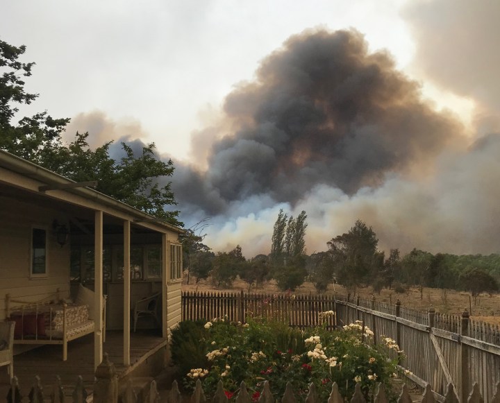 Cottage garden and weatherboard cottage with fire in distance