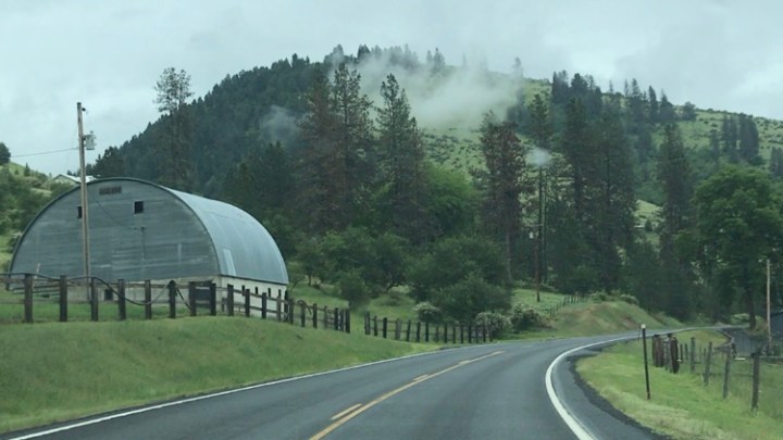 Round topped barn in Idaho with misty mountains, photo by Ray Monde