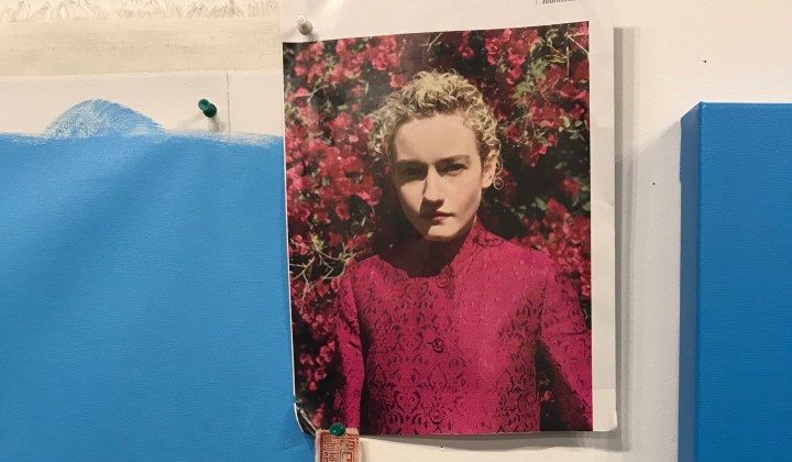 Women in pink with bouganvillia between two blue canvases
