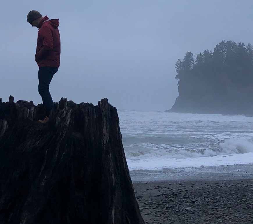 Artist Ray Monde standing on a giant stump at La Push, Washington
